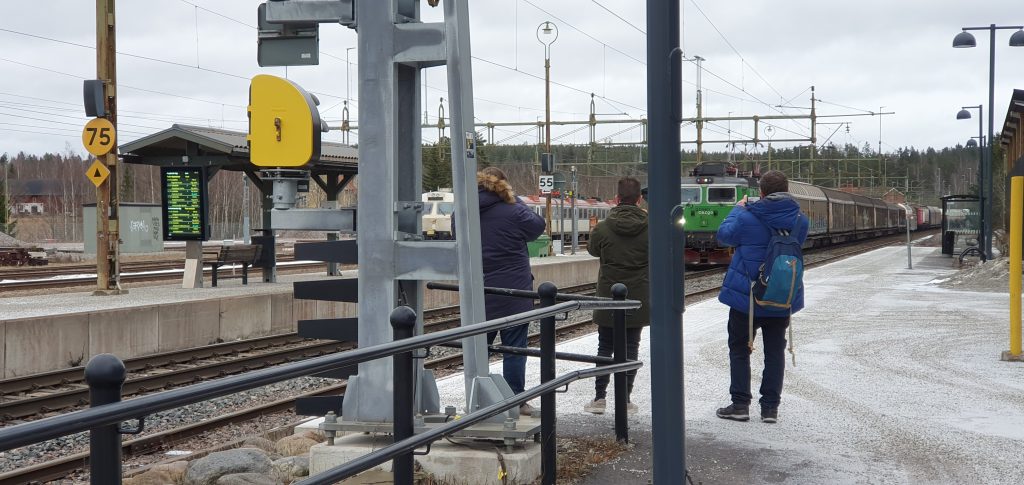 Tre personer fotograferar ett ankommande tåg