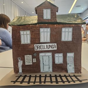 Stationshus i papier machémed skylt och räls